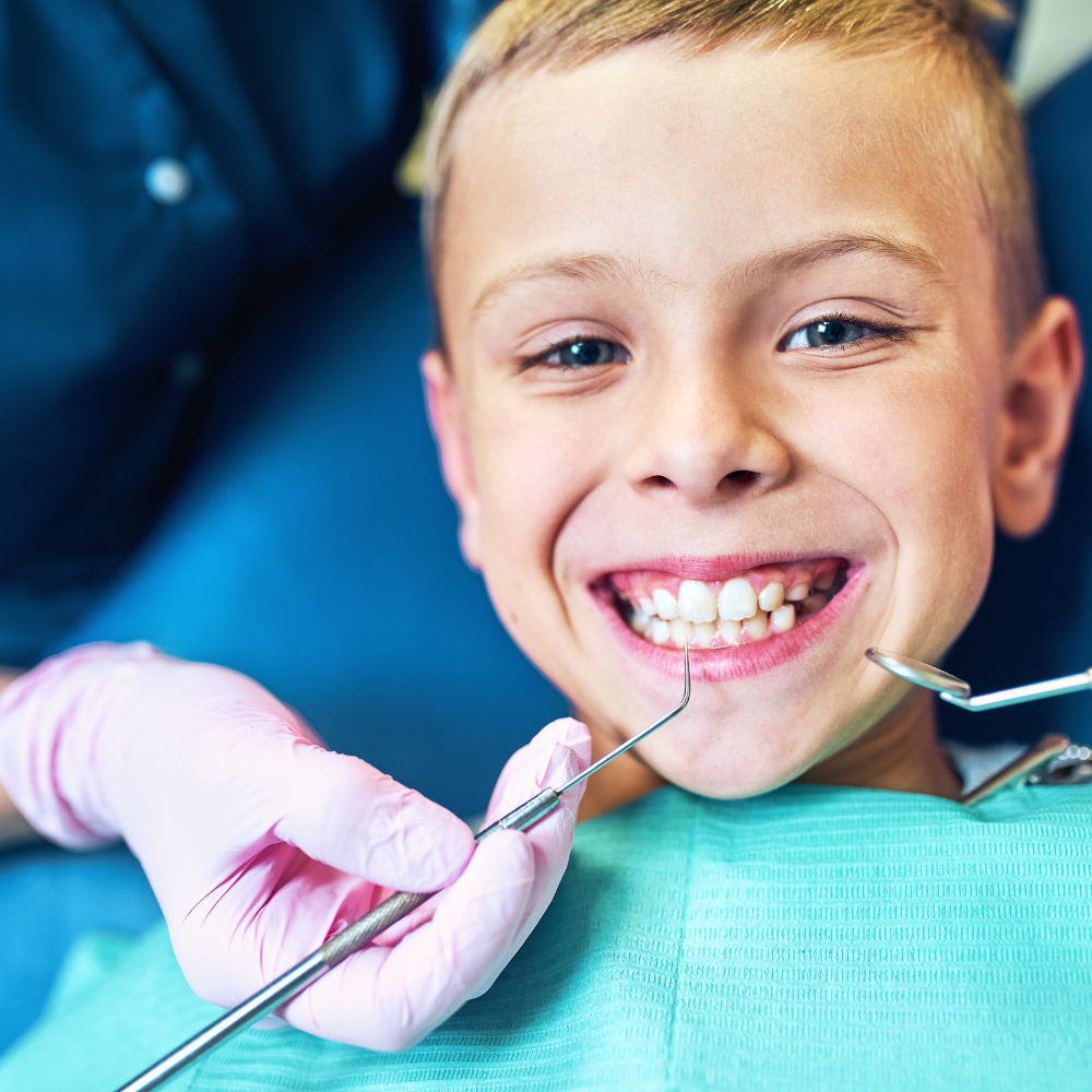 young boy smiling in dentist chair 
